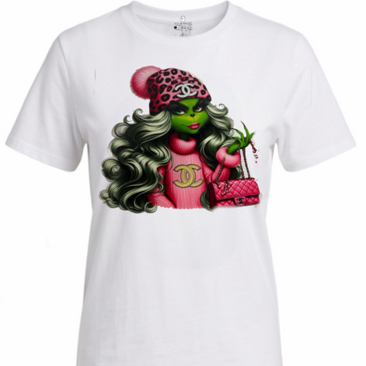 A white short-sleeve crewneck t-shirt featuring a colorful graphic print of a green-skinned woman with long wavy hair, wearing a pink and black leopard-print hat and a pink Chanel-style top, holding a pink quilted handbag.