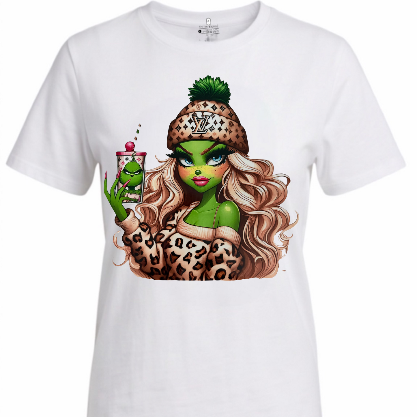 A white short-sleeve crewneck t-shirt featuring a large graphic print of a green-skinned cartoon woman with long wavy brown hair, wearing a leopard-print beanie and holding a drink.