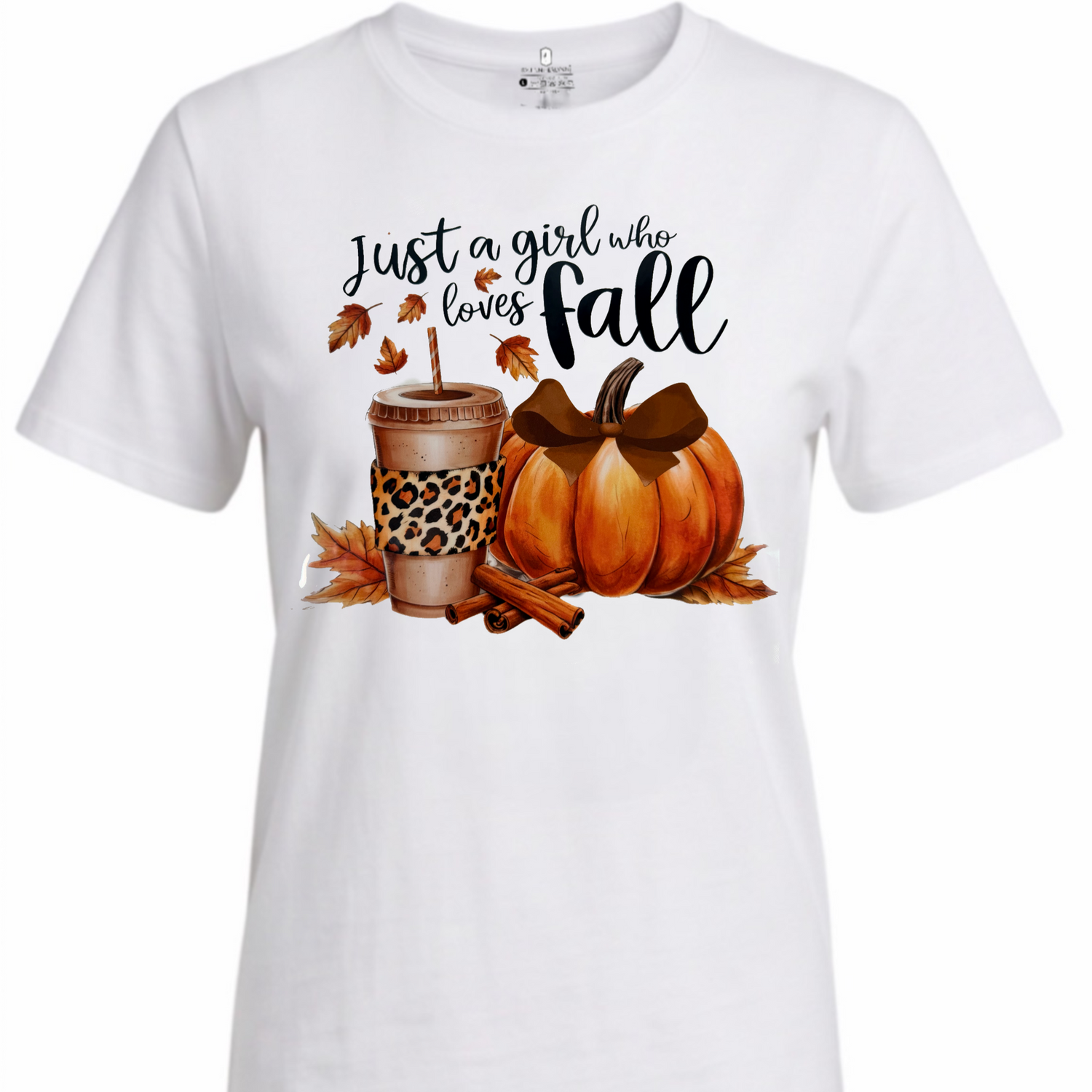 A white short-sleeve crewneck t-shirt featuring a fall-themed graphic print with the text 'Just a girl who loves fall' above a cup with leopard print, a pumpkin, leaves, and cinnamon sticks.