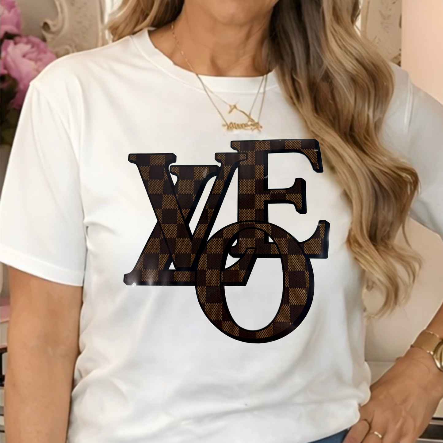 a white t-shirt with a brown checkerboard patterned 'LOVE' graphic