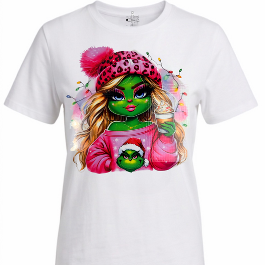 A white short-sleeve crewneck t-shirt featuring a colorful graphic print of a green-skinned cartoon character with a pink leopard-print beanie and a Santa hat, holding a drink.