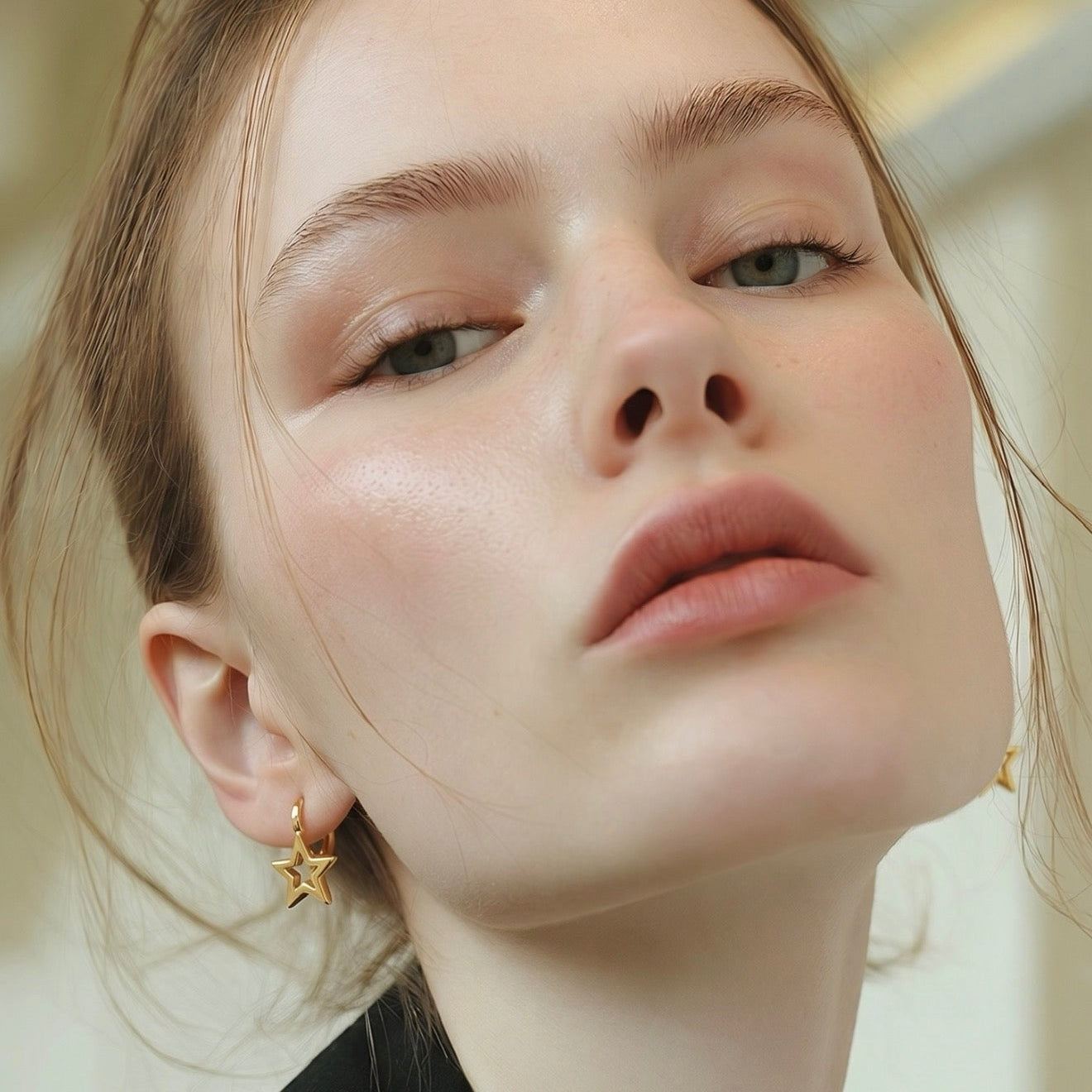 Close-up of a person wearing an earring with a tree of life design.