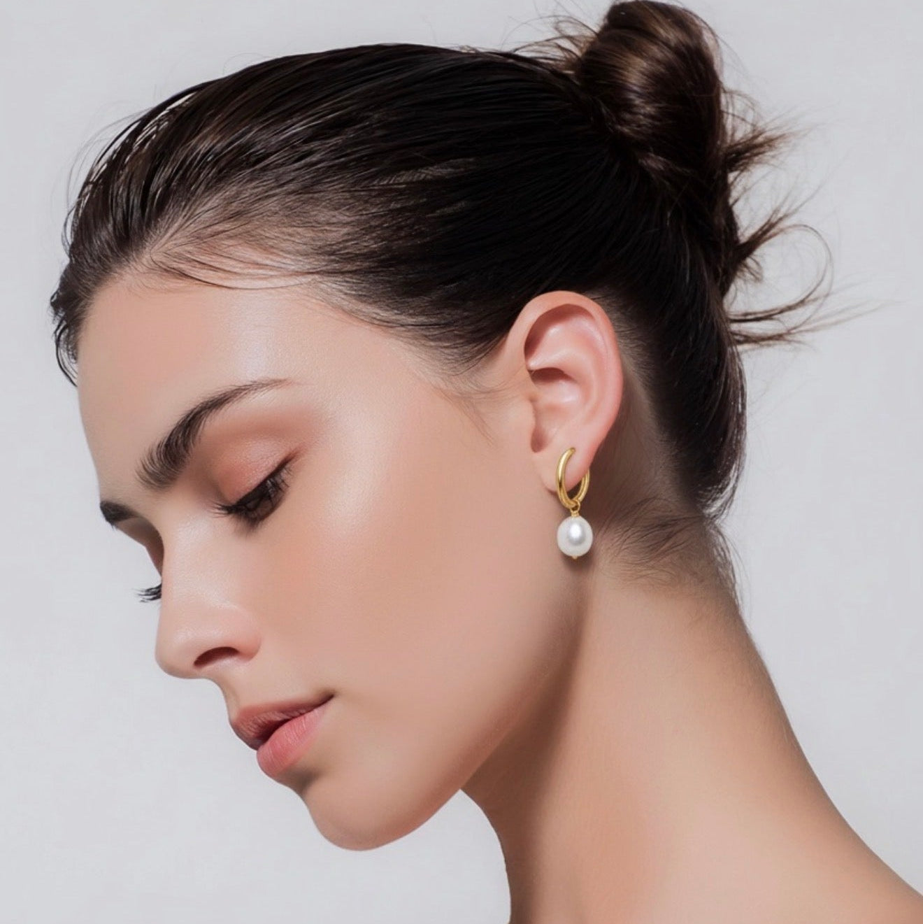 Woman wearing pearl earrings against a plain background