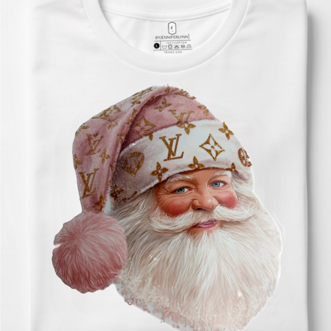 A folded white t-shirt featuring a large graphic print of a Santa Claus face wearing a pink and white Louis Vuitton monogram Santa hat, set against a clean white background.