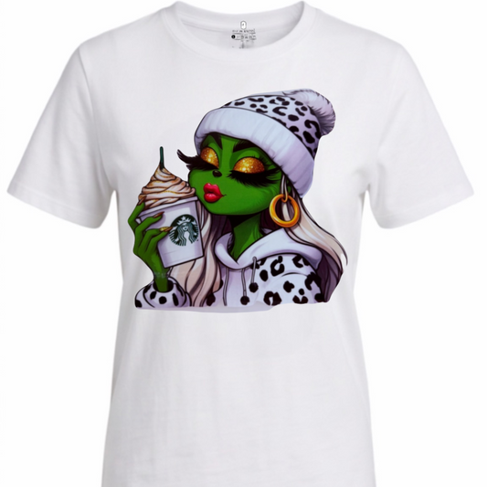 A white short-sleeve crewneck t-shirt featuring a colorful graphic print of a green-skinned woman with long blonde hair, wearing a black and white leopard print beanie and matching top, holding a Starbucks cup.