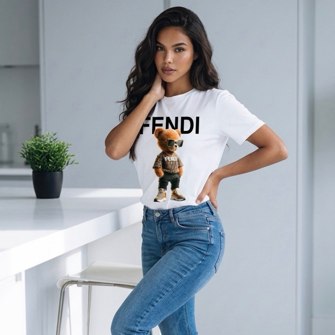 Woman wearing a white t-shirt with a teddy bear graphic and 'Fendi' branding in a modern kitchen.