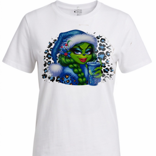 A white short-sleeve crewneck t-shirt featuring a colorful graphic print of a green Grinch-like character wearing a blue Santa hat and holding a blue drink, set against a plain white background.